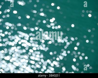 Draufsicht auf die Wasseroberfläche. Verschwommene Unschärfe mit Bokeh-Effekt. Sonnenlicht auf dem Wasser. Hintergrund abstrakte Hintergrundstruktur. Stockfoto