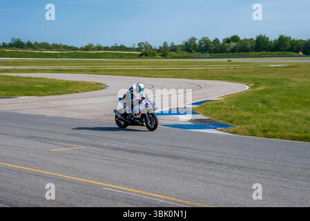 Motorradfahrer auf einer Rennstrecke bei Tageslicht in eine Kurve Stockfoto