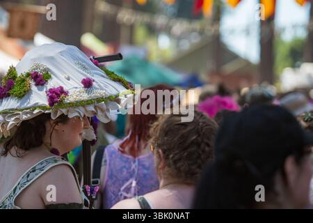 Farbenfrohe Renaissance Festival Maskerade Vendor Stand mit Kostümen, Blumendekorationen und mittelalterlichen Accessoires Stockfoto