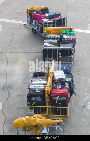 ALANYA, TÜRKEI, 10.07.2018: Gepackte Gepäckwagen mit diversen Koffern, die den Flughafenbetrieb und die Reisebereitschaft auf einem Rollfeld zeigen. Stockfoto