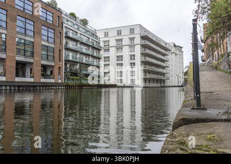 Moderne und historische Gebäude spiegeln sich an einem bewölkten Tag im ruhigen Wasser des Regent's Canal in der Stadt london wider Stockfoto