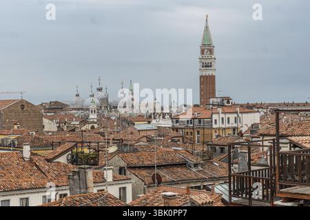 Rote Ziegeldächer, Schornsteine und Kirchtuppeln dominieren die venezianische Skyline mit saint Marks campanile, die sich über dem Stadtbild erhebt Stockfoto