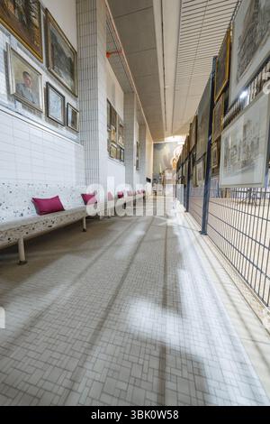 Ein langer Korridor in einer Kunstgalerie mit zahlreichen Gemälden an den Wänden und einer weißen Bank mit roten Kissen, historische Kunstausstellung im alten Swimm Stockfoto