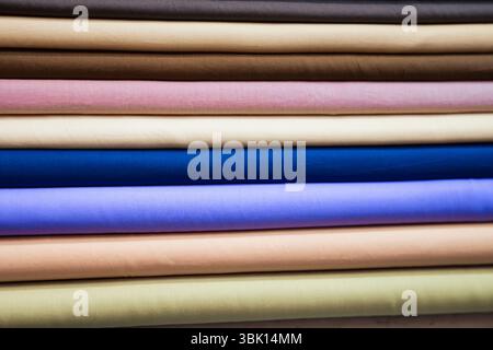 Eine Nahaufnahme zeigt einen sorgfältig angeordneten Stapel von Stoffrollen, die eine vielfältige Palette an Farben und Texturen zeigen. Jede Rolle wird angezeigt Stockfoto