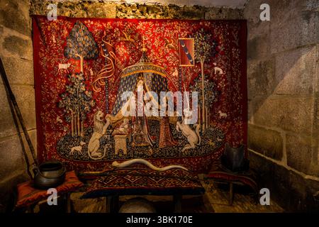 Nachbildung des Wandteppichs aus der Serie „die Dame mit dem Einhorn“. 1841 besuchte der Schriftsteller George Sand die Burg und entdeckte die berühmten mittelalterlichen Wandteppiche, die später vom Denkmalkonservator und Schriftsteller Prosper Mérimée verifiziert wurden. Heute sind sie im Musée de Cluny in Paris zu sehen. George Sand entdeckte bei ihrem Besuch insgesamt sechs Wandteppiche. Ihre Annahme, dass es sich um mittelalterliche Schätze handelte, war richtig. Die Wandteppiche wurden wahrscheinlich zwischen 1484 und 1500 in Flandern gewebt. Rue de la Cure, Boussac, Nouvelle-Aquitaine, Frankreich Stockfoto