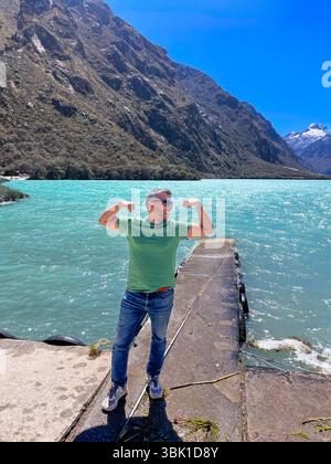 Ein Mann in einem grünen Hemd steht auf einem Dock am Wasser. Er beugt seinen Arm und blickt auf das Wasser. Die Szene ist friedlich und ruhig, mit Stockfoto