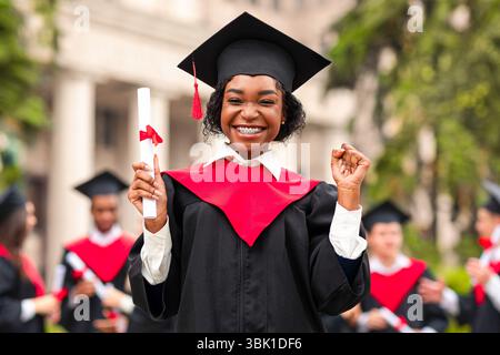 Fröhliche afroamerikanische junge Dame im Abschlusskostüm Stockfoto