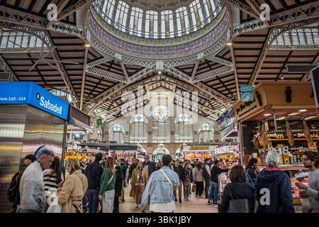 VALENCIA, SPANIEN - 15. APRIL 2025: Mercat Central ist voller Käufer durch eine Eisenkuppel, die Imbissstände und die Marktkultur der Stadt hervorhebt. Mercado Central, Stockfoto