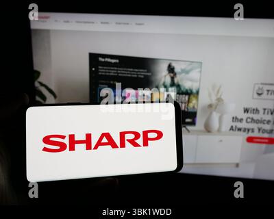 Stuttgart, Deutschland - 26.04.2025: Person mit Smartphone und Logo des Elektronikunternehmens Sharp Corporation auf dem Bildschirm vor der Website. Stockfoto