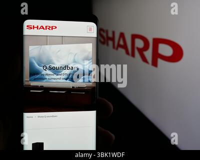 Stuttgart, Deutschland - 26.04.2025: Person, die ein Mobiltelefon hält, mit Webseite des Elektronikunternehmens Sharp Corporation vor dem Logo auf dem Bildschirm. Stockfoto
