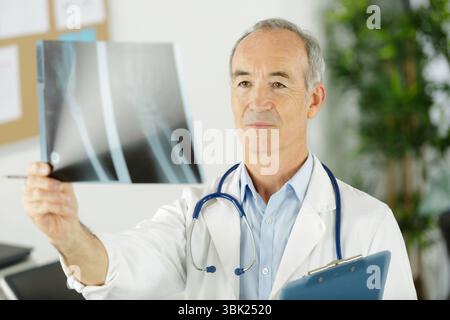 Senior männlicher Arzt mit Röntgenbild Stockfoto