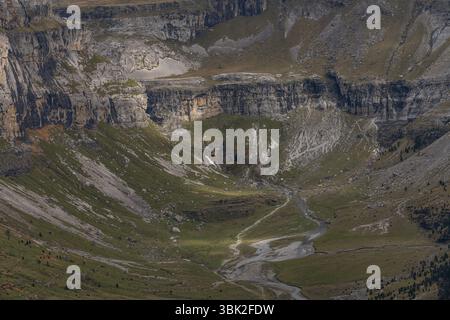 Hoch aufragende Klippen mit Blick auf einen dichten Wald und schneebedeckte Gipfel schaffen einen atemberaubenden Kontrast aus Texturen und Farben. Stockfoto