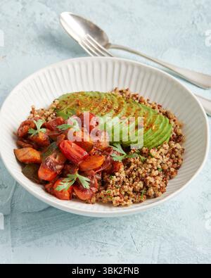 Gesunde Quinoa-Schüssel mit Avocado, Nüssen und Tomaten – ein farbenfrohes, pflanzliches Mittag- oder Abendessen. Stockfoto