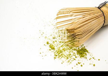 Matcha Grünteepulver mit einem traditionellen Bambusbesen oder chasen auf weißem Hintergrund. Zubehör für die Zubereitung von Matcha-Grüntee Stockfoto
