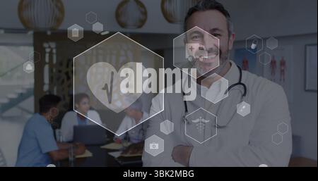 Lächelnder männlicher Arzt, der im Besprechungsraum des Krankenhauses steht, mit Stethoskop und schwimmenden medizinischen Ikonen Stockfoto