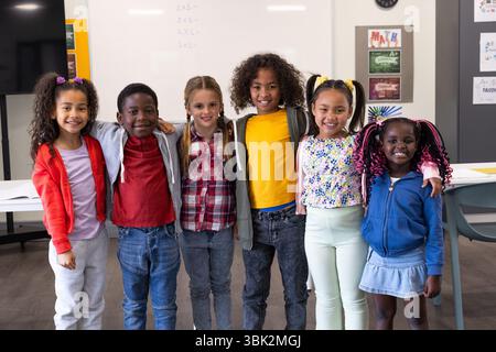 Verschiedene Gruppen lächelnder Kinder stehen zusammen im Klassenzimmer und genießen die Schule Stockfoto