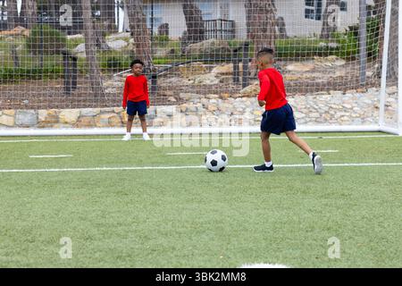 Verschiedene Jungen spielen Fußball auf dem Feld, ein Ball zum Tor, Spaß im Freien Stockfoto