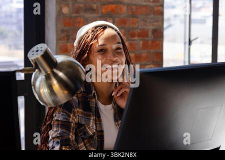 Frau programmiert am Computer, lächelt im modernen Büro Stockfoto