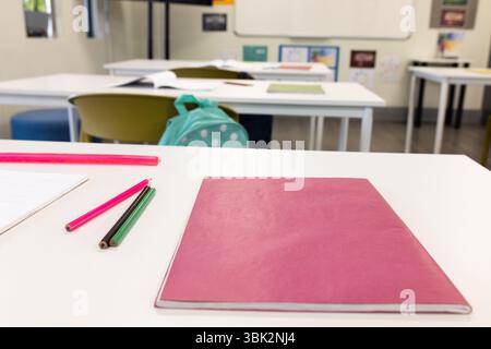 Klassenzimmer mit Notizbüchern und Bleistiften auf dem Schreibtisch, bereit für Lernaktivitäten in der Schule Stockfoto