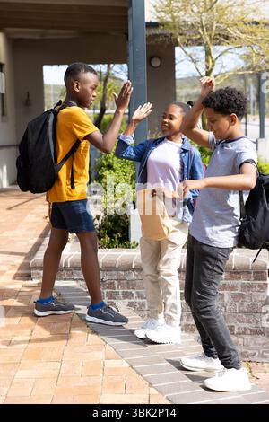 Schule verschiedene Freunde, die High-Five und Lachen draußen, genießen sonnigen Nachmittag zusammen Stockfoto