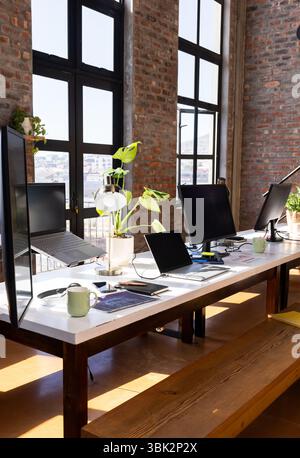 Moderner Büroarbeitsplatz mit mehreren Laptops und Monitoren auf Holztisch, Kopierraum Stockfoto