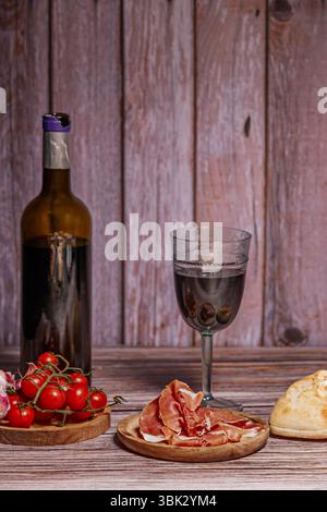 Scheiben Serrano-Schinken mit Oliven oder Käse: Schinken wird oft mit einer kleinen Beilage serviert, um seinen Geschmack zu verbessern. Stockfoto