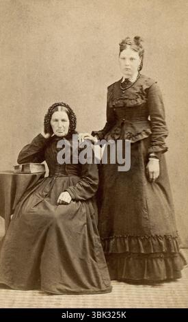 Hertfordshire, England. Um 1870 – Ein Atelierporträt Carte de Visite Foto von Sarah Drage (1814–1888) und ihrer Tochter Rose Esther Drage (1857–1905) aus Royston, Hertfordshire. Aufgenommen um 1870 vom Fotografen William Norman aus der High Street, Royston. Sarah sitzt mit dem Ellenbogen auf einer Bibel, und Rose steht mit der Hand auf der Schulter ihrer Mutter. Stockfoto