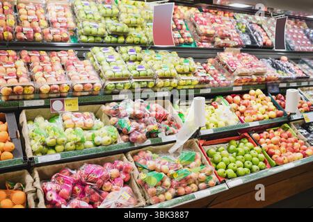 Verpackte Äpfel werden in den Regalen des Supermarktes in flacher Form mit Tabletts, Taschen, Körben ausgestellt Stockfoto