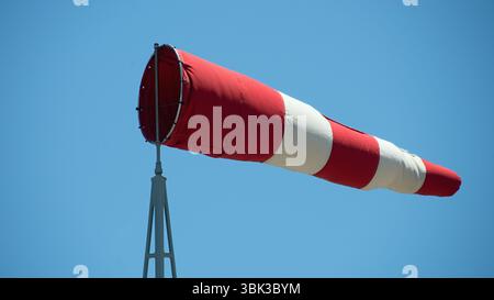 Windsockenanzeige für Wind. Windkegel zeigt Windrichtung und -Kraft an. Horizontal fliegende Windsocke mit blauem Himmel im Hintergrund Stockfoto