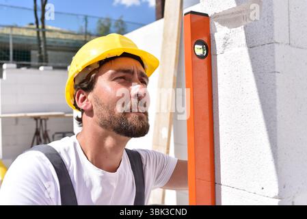 Berufsbauarbeiter - Arbeit auf einer Baustelle Bau eines Wohnhauses - Qualitätskontrolle Stockfoto