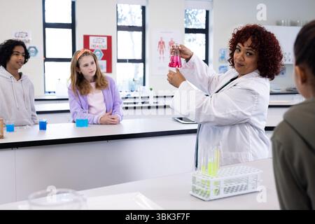 In der Schule demonstrierte Lehrerin Chemieexperimente vor verschiedenen Schülern im Wissenschaftslabor Stockfoto