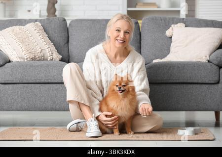 Reife Frau, die zu Hause süßen Pommerschen Hund füttert Stockfoto