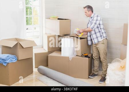 Offene Kartonschachteln liegen im Eingangsbereich, mit Luftpolsterfolie und Verpackungsband-Spender Stockfoto