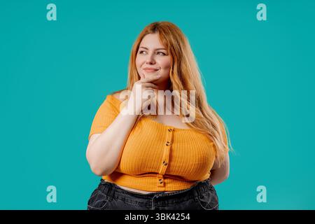 Nachdenklich um körperpositive Frau auf Blau. Verwirrte Dame, die nach einer Antwort sucht Stockfoto