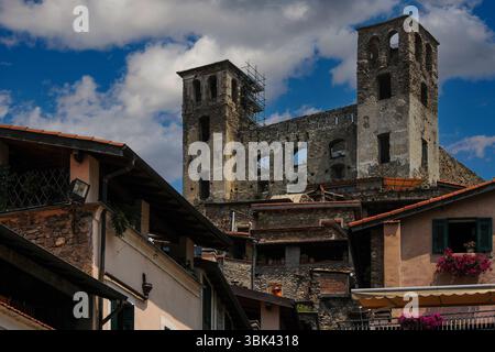 Narben der Schlacht: Renaissance-Fresken auf dem quadratischen Turm aus dem 16. Jahrhundert der Ruine der mittelalterlichen Burg Doria oder Castello dei Doria in Dolceacqua, Ligurien, Italien, gespickt mit Löchern, die 1744 von französisch-spanischen Kanonenkugeln hinterlassen wurden. Die Festung aus dem 12. Jahrhundert, die hier repariert wurde, war die Heimat der Doria-Herrscher von Genua. 1884 malte der französische Impressionist Claude Monet die Burg und die nahe gelegene Ponte Vecchio, die den Fluss Nervia überspannte. Stockfoto