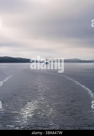 Die Fähre segelt durch das ruhige Wasser des Oslofjords in Akershus Norwegen, umgeben von Morgennebel und Nebel, ruhige Atmosphäre inmitten fernen Hügeln Stockfoto