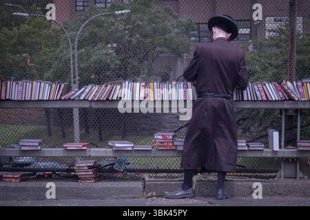 Ein anonymer orthodoxer jüdischer Mann kauft religiöse Bücher bei einem Pop-up-Verkauf auf der BQE-Überführung an der Lee Avenue. In Williamsburg, Brooklyn, New York. Stockfoto