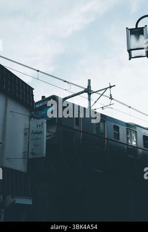 Ein Zug der JR Yamanote Line gleitet über eine enge Straße Tokios Stockfoto