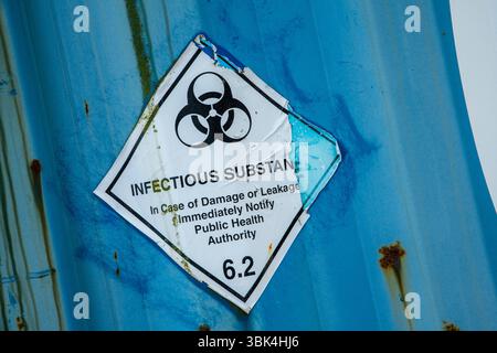 Aufkleber für verwitterte und abblätternde infektiöse Substanzen mit einem Symbol für biologische Gefahrstoffe auf einer Metalloberfläche, das vor gefährlichen Stoffen warnt. Stockfoto
