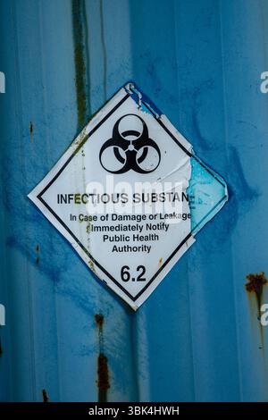 Aufkleber für verwitterte und abblätternde infektiöse Substanzen mit einem Symbol für biologische Gefahrstoffe auf einer Metalloberfläche, das vor gefährlichen Stoffen warnt. Stockfoto