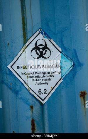 Aufkleber für verwitterte und abblätternde infektiöse Substanzen mit einem Symbol für biologische Gefahrstoffe auf einer Metalloberfläche, das vor gefährlichen Stoffen warnt. Stockfoto