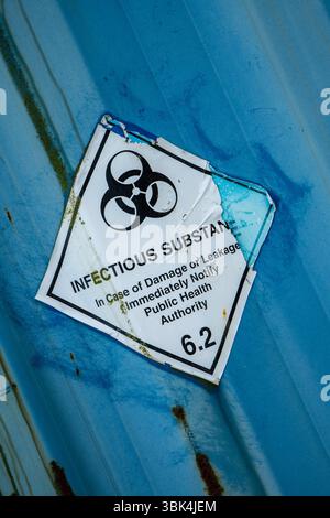 Aufkleber für verwitterte und abblätternde infektiöse Substanzen mit einem Symbol für biologische Gefahrstoffe auf einer Metalloberfläche, das vor gefährlichen Stoffen warnt. Stockfoto