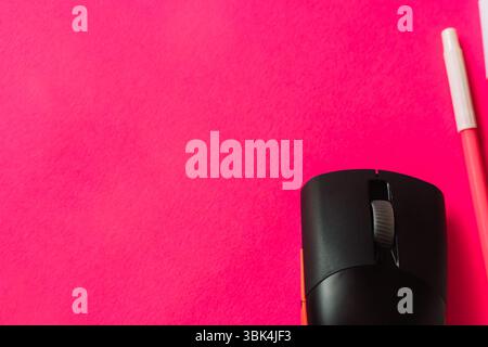 Nahaufnahme einer schwarzen kabellosen Computermaus und eines rosafarbenen Stiftes auf einem leuchtend rosa Hintergrund. Flache Ladefläche für kreativen Arbeitsplatz oder technisches Konzept. Stockfoto