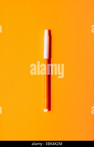 Leuchtend orangefarbener Marker mit weißer Kappe auf leuchtendem orangefarbenem Hintergrund, minimales Back-to-School-Pop-Art-Konzept. Stockfoto