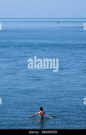 Eine Schwimmerin genießt das Wasser am Strand von Exmouth in Devon, da für den größten Teil Englands gelbe Hitzewarnungen ausgegeben wurden. Stockfoto