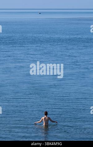Eine Schwimmerin genießt das Wasser am Strand von Exmouth in Devon, da für den größten Teil Englands gelbe Hitzewarnungen ausgegeben wurden. Stockfoto
