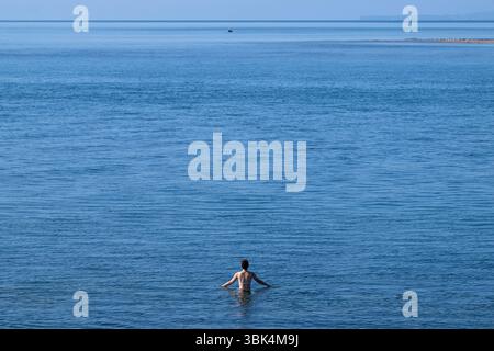 Eine Schwimmerin genießt das Wasser am Strand von Exmouth in Devon, da für den größten Teil Englands gelbe Hitzewarnungen ausgegeben wurden. Stockfoto