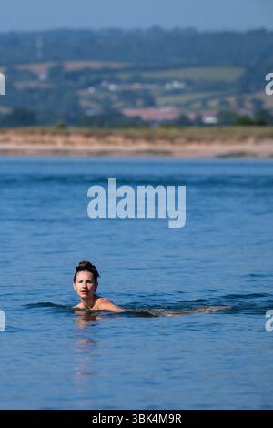 Eine Schwimmerin genießt das Wasser am Strand von Exmouth in Devon, da für den größten Teil Englands gelbe Hitzewarnungen ausgegeben wurden. Stockfoto