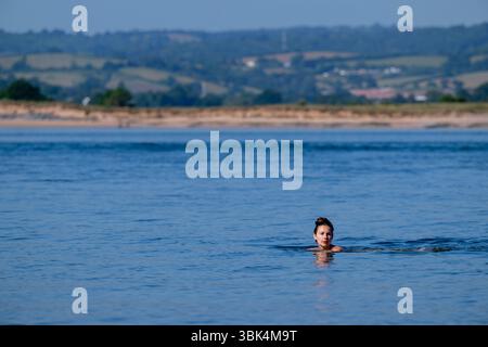 Eine Schwimmerin genießt das Wasser am Strand von Exmouth in Devon, da für den größten Teil Englands gelbe Hitzewarnungen ausgegeben wurden. Stockfoto