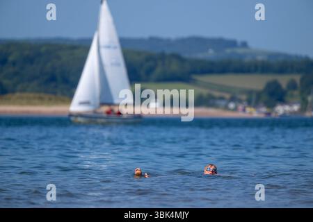 Eine Schwimmerin genießt das Wasser am Strand von Exmouth in Devon, da für den größten Teil Englands gelbe Hitzewarnungen ausgegeben wurden. Stockfoto